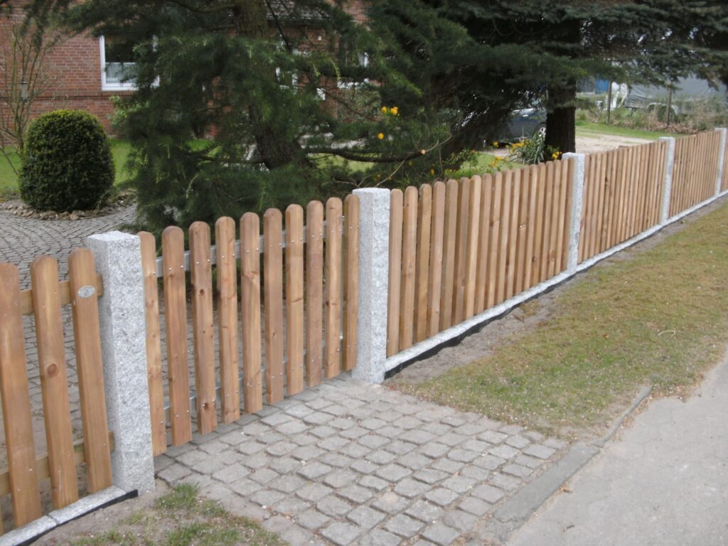 Solider Holzzaun mit Granitpfosten von Klingenberg Zäune – natürliche Grundstücksgrenze in Garbsen.