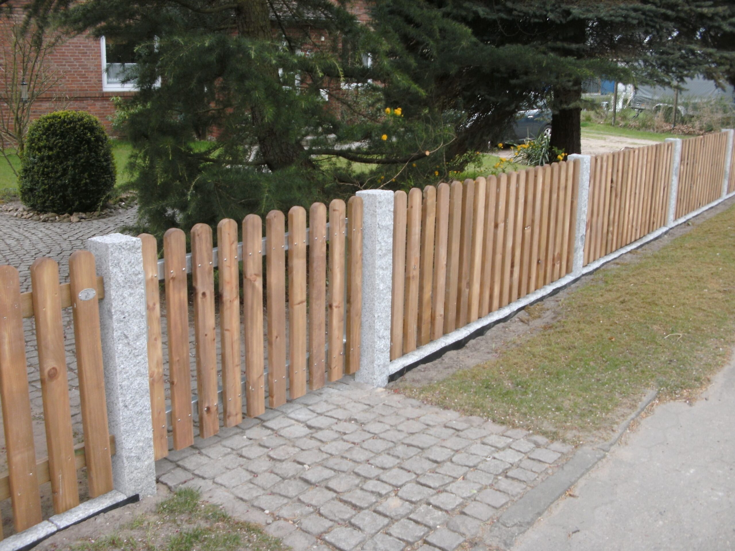 Solider Holzzaun mit Granitpfosten von Klingenberg Zäune – natürliche Grundstücksgrenze in Garbsen.