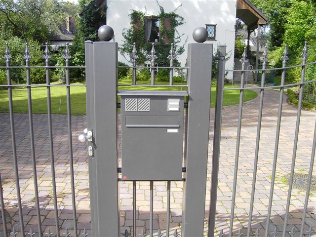 Klingenberg Zaeune installiert graues Schmiedetor mit integriertem Briefkasten und Zaunspitzen, sichert die Einfahrt.