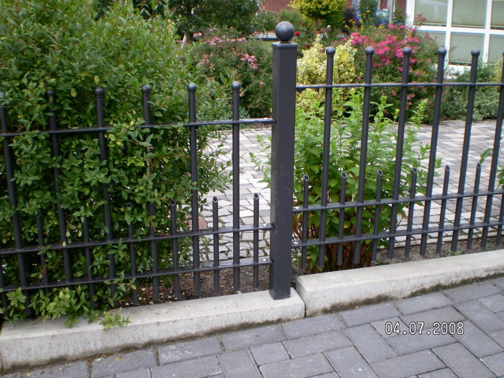 Zierzaun mit Kugelpfosten von Klingenberg Zaeune in Hannover schafft klare Begrenzung und unterstreicht den blühenden Vorgarten.