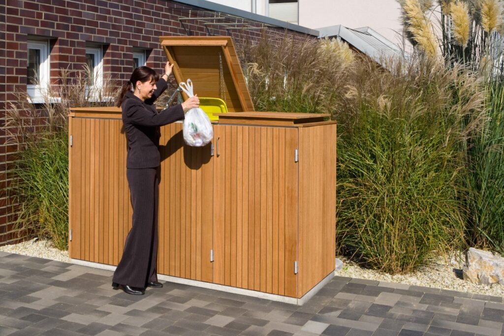 Mülltonnenbox im Holzdesign mit geöffnetem Klappdeckel für Gelbe Tonne – stilvolle Mülltonnenverkleidung von Klingenberg-Zäune aus Garbsen für Hannover und die Region